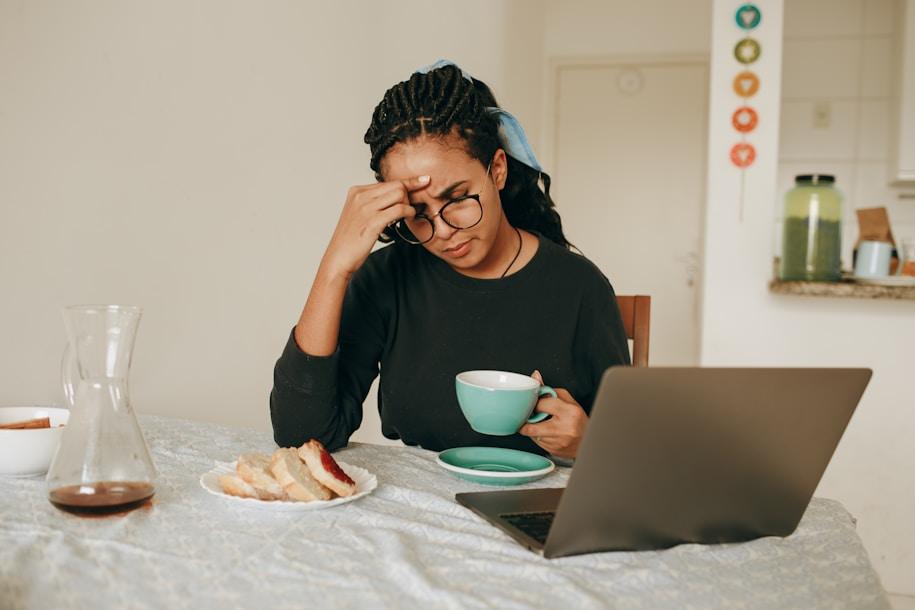 Woman feeling stressed while working from home with laptop and coffee